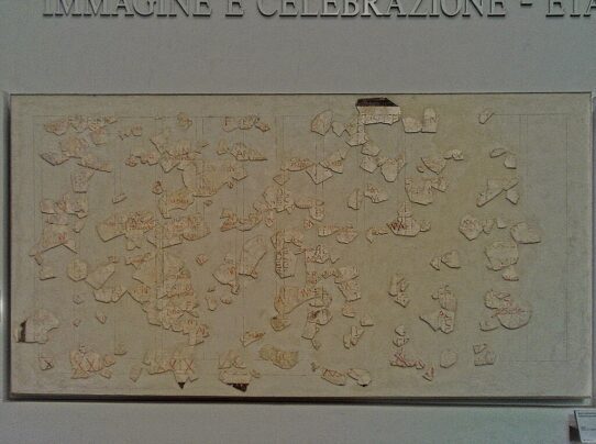 Fragment of the Fasti Antiates, an ancient Roman calendar painted on plaster, showing month names, festival markings, and preserved red and black inscriptions.