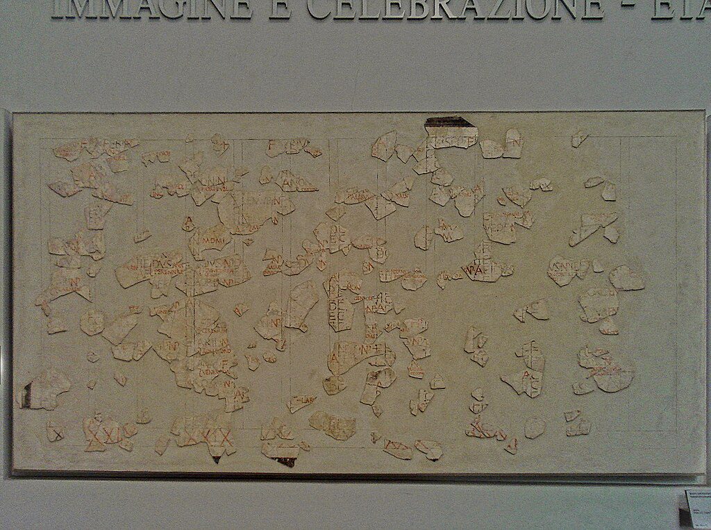 Fragment of the Fasti Antiates, an ancient Roman calendar painted on plaster, showing month names, festival markings, and preserved red and black inscriptions.